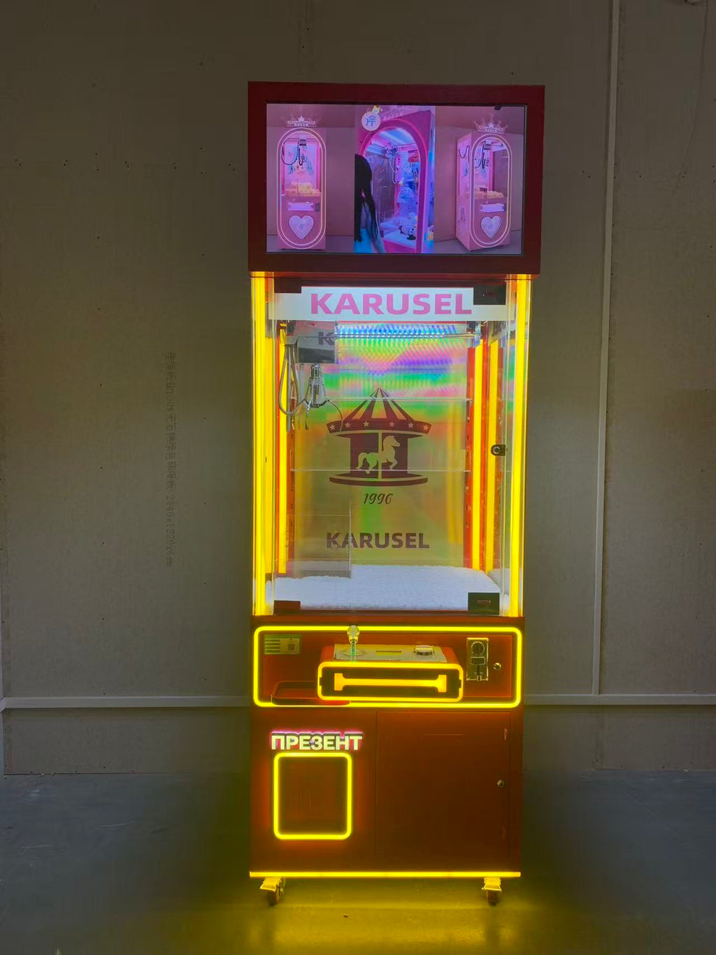 Video game arcade with doll catching machines featuring advertising screens and holding figurines for games and gift dispensers