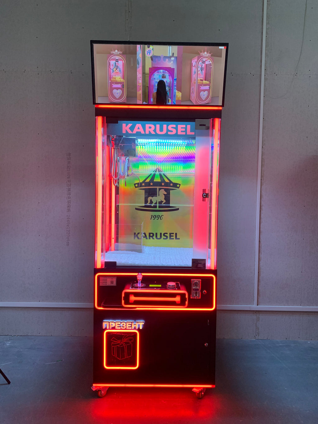 claw machine  with advertising screen featuring collectible figurines and electronic games.