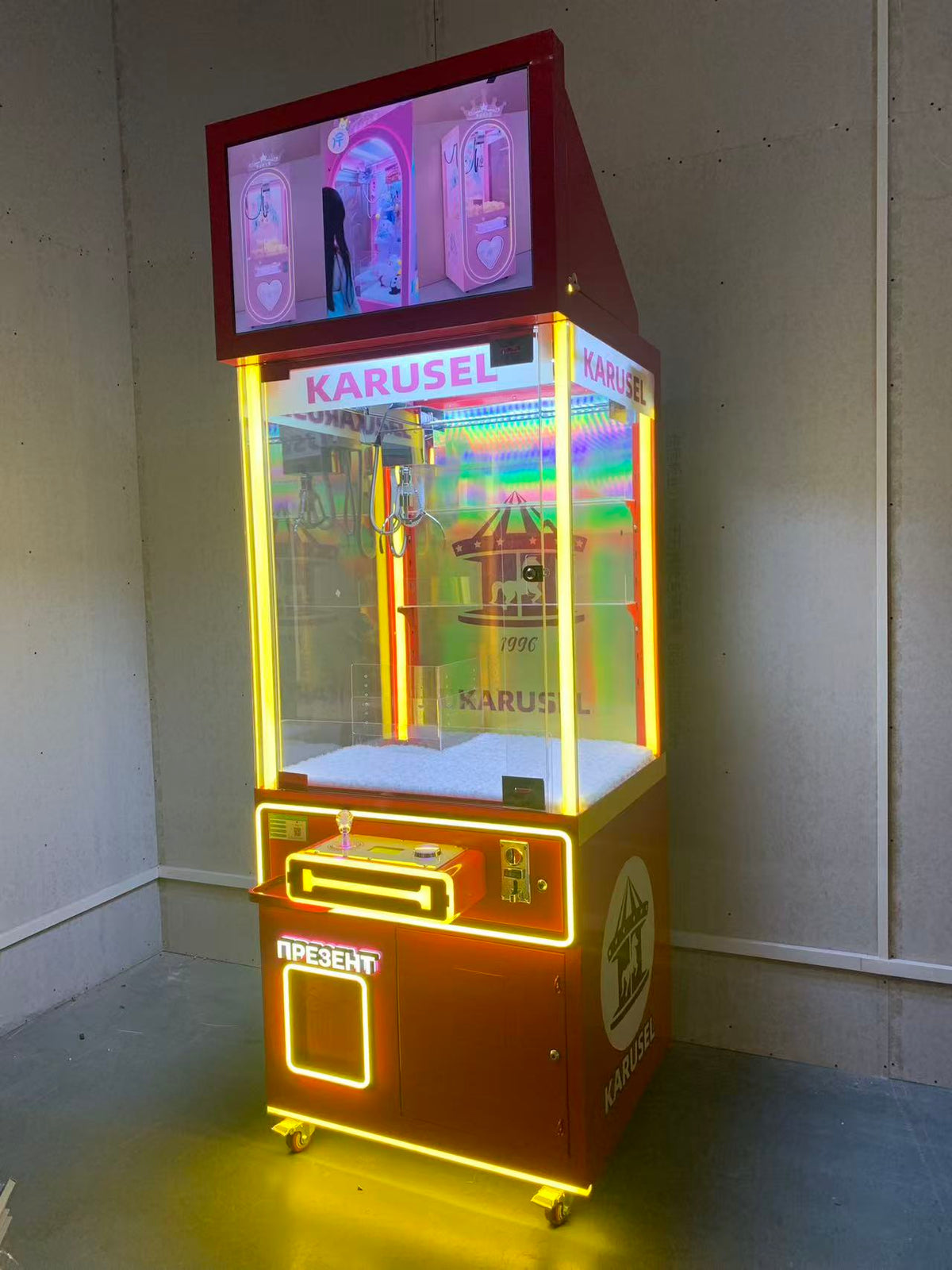 Video game arcade with doll catching machines featuring advertising screens and holding figurines for games and gift dispensers
