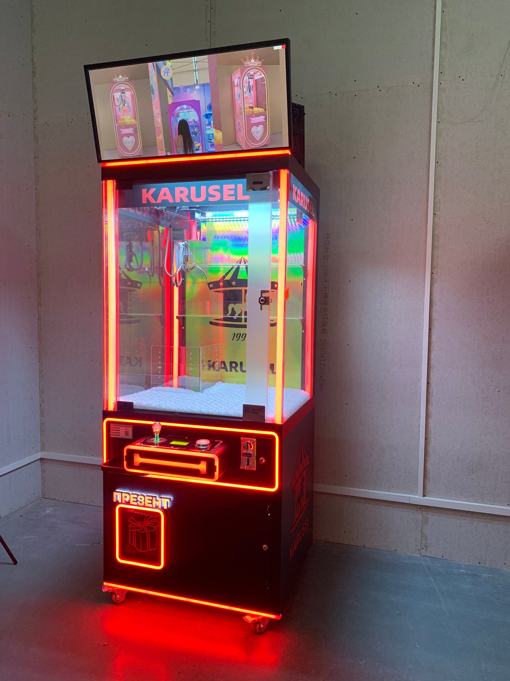 claw machine  with advertising screen featuring collectible figurines and electronic games.
