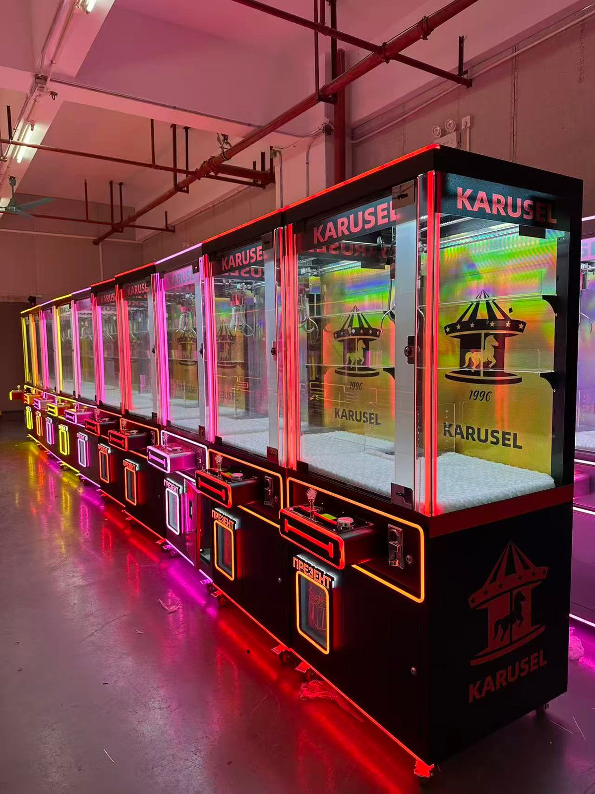 Video game arcade with doll catching machines featuring advertising screens and holding figurines for games and gift dispensers
