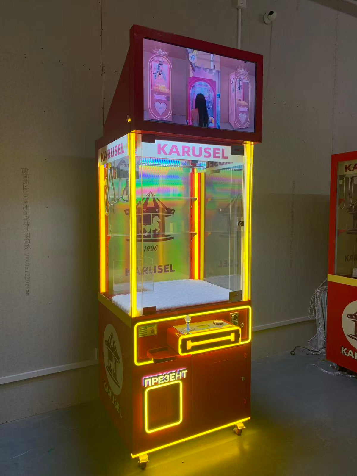 Video game arcade with doll catching machines featuring advertising screens and holding figurines for games and gift dispensers