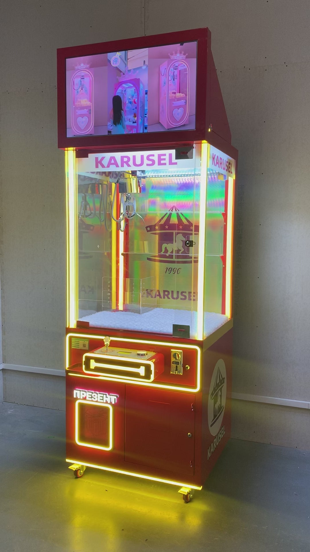 Video game arcade with doll catching machines featuring advertising screens and holding figurines for games and gift dispensers